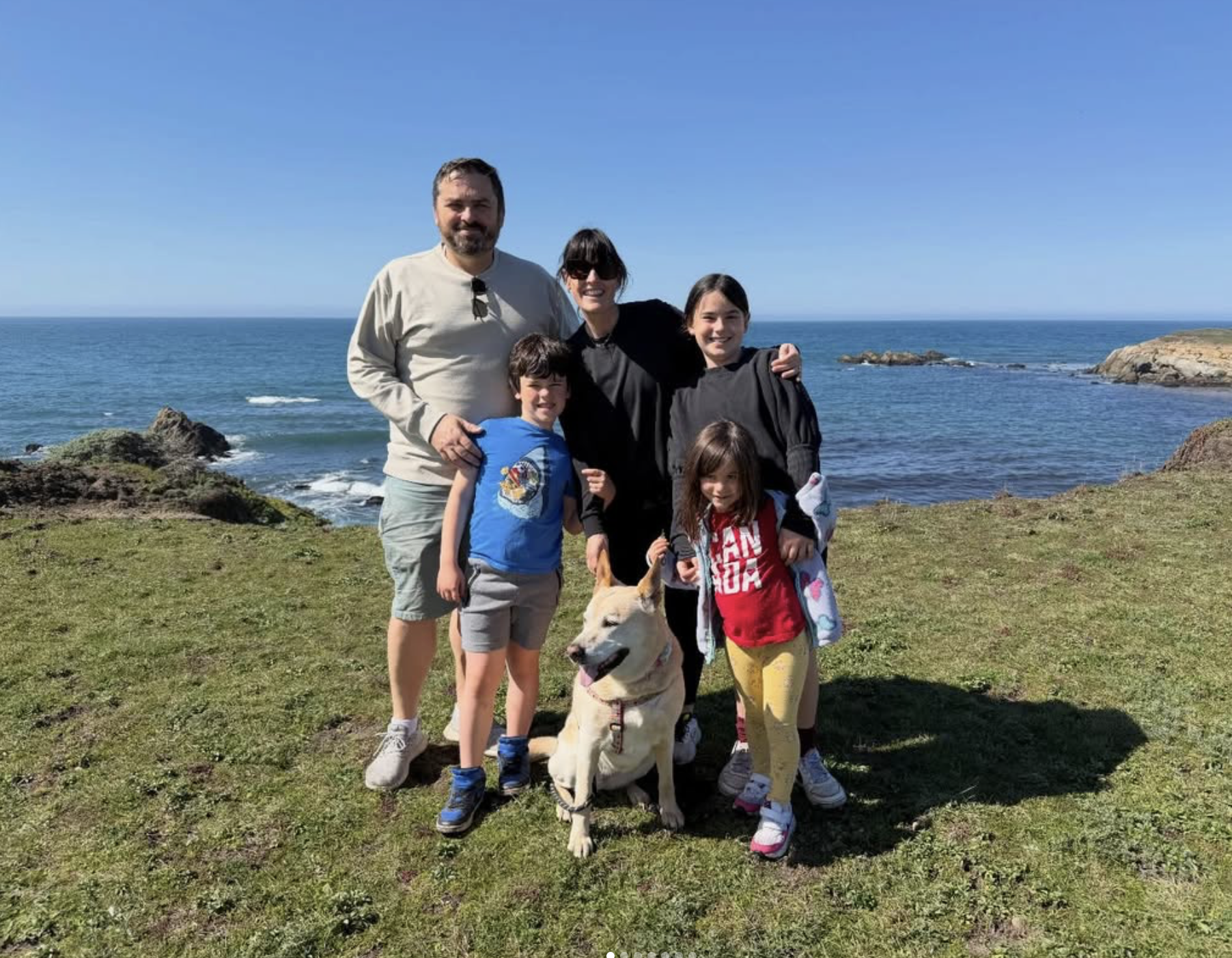 The Cooney family with their dog on a coastal bluff overlooking the ocean
