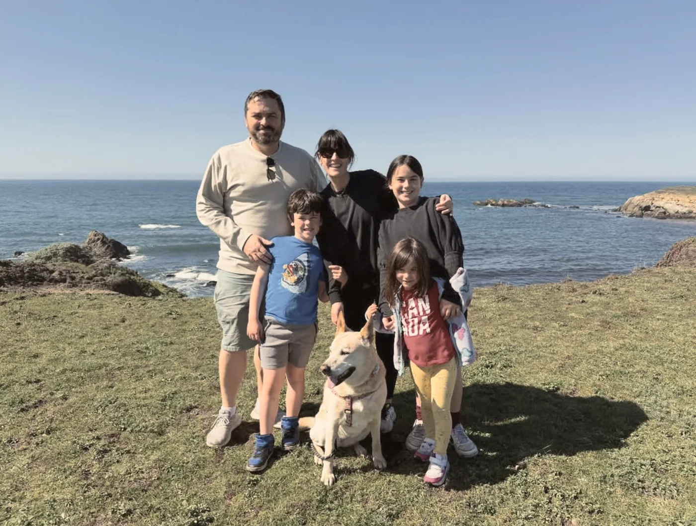 The Cooney family with their dog on a coastal bluff overlooking the ocean