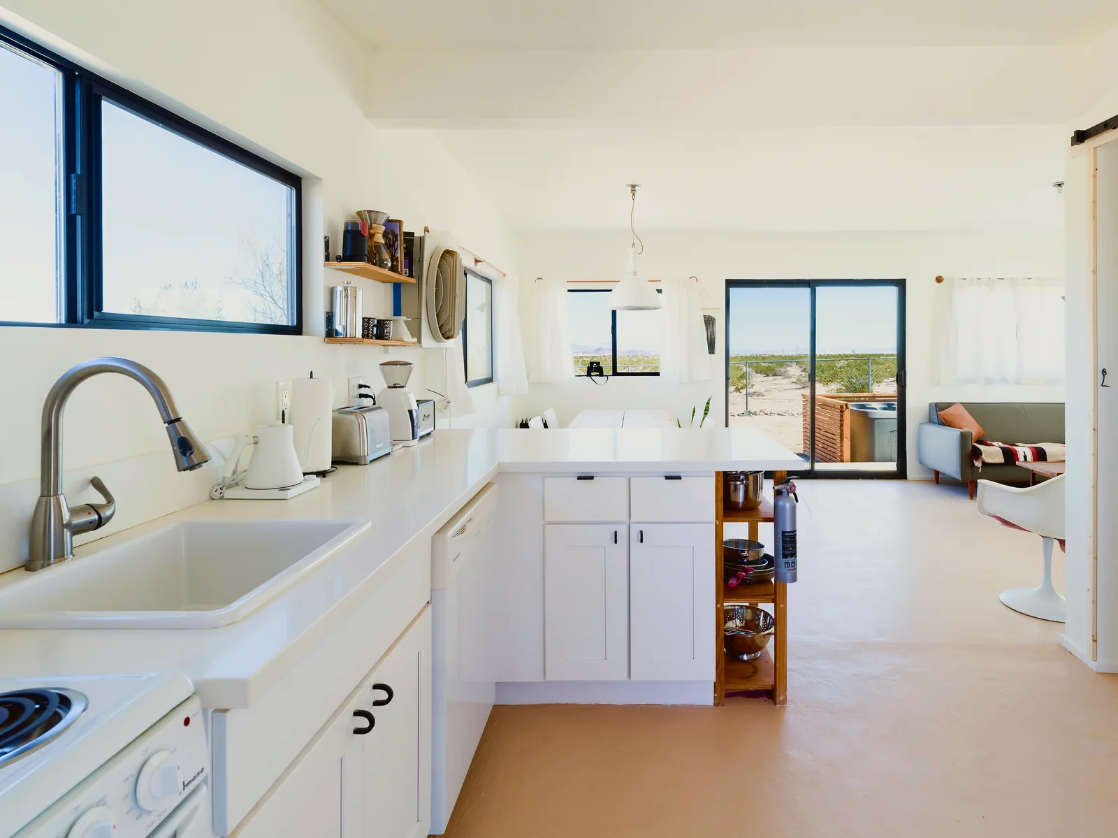 Bright white kitchen in the Joshua Tree cabin with sliding doors out to the desert