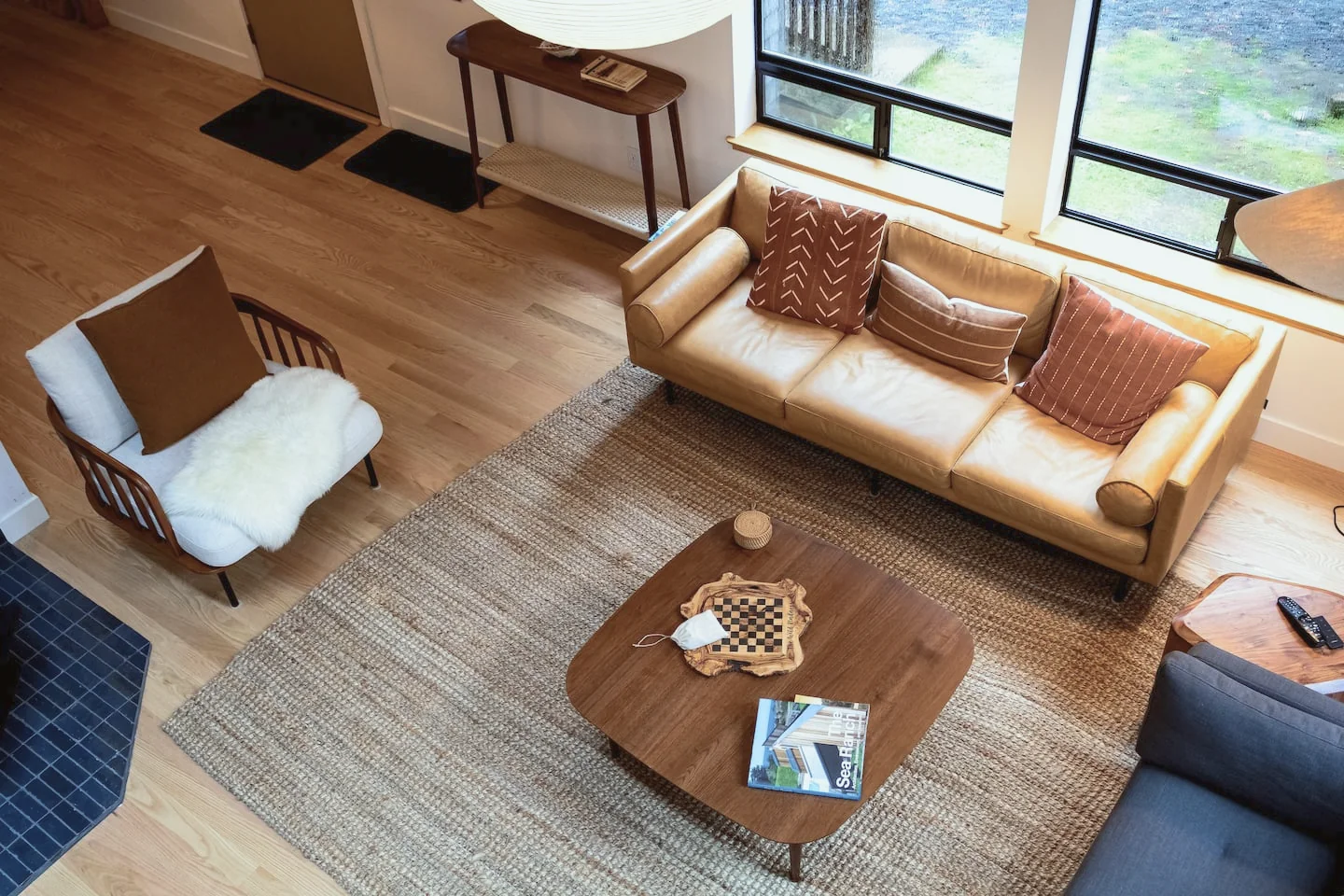 Sea Ranch living room from above, with a leather sofa, jute rug and walnut coffee table