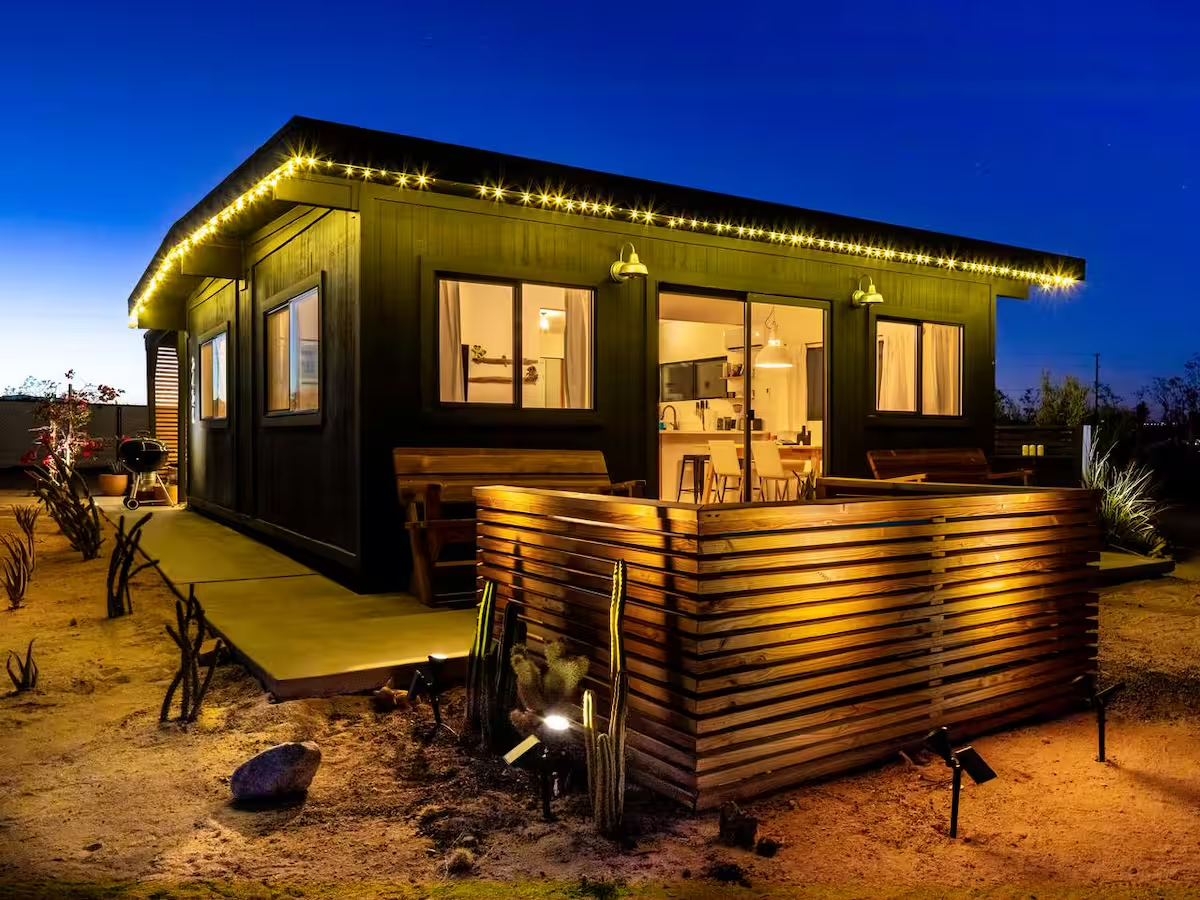 Joshua Tree cabin lit up at dusk with string lights