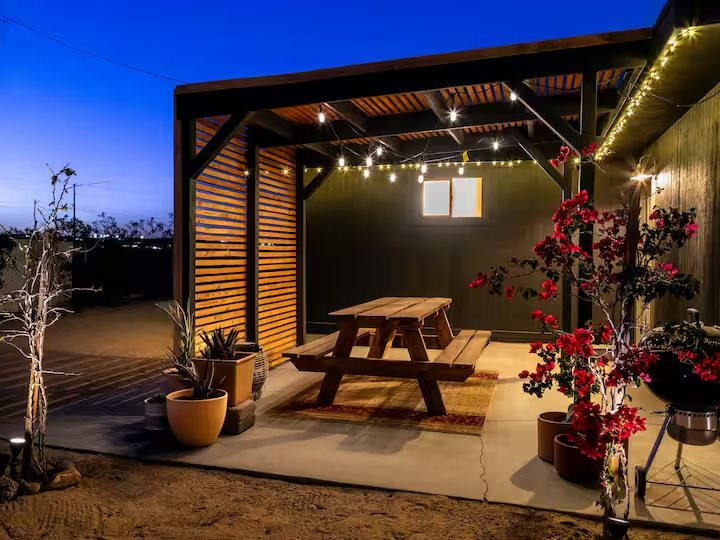 Joshua Tree covered patio with picnic table and string lights at dusk