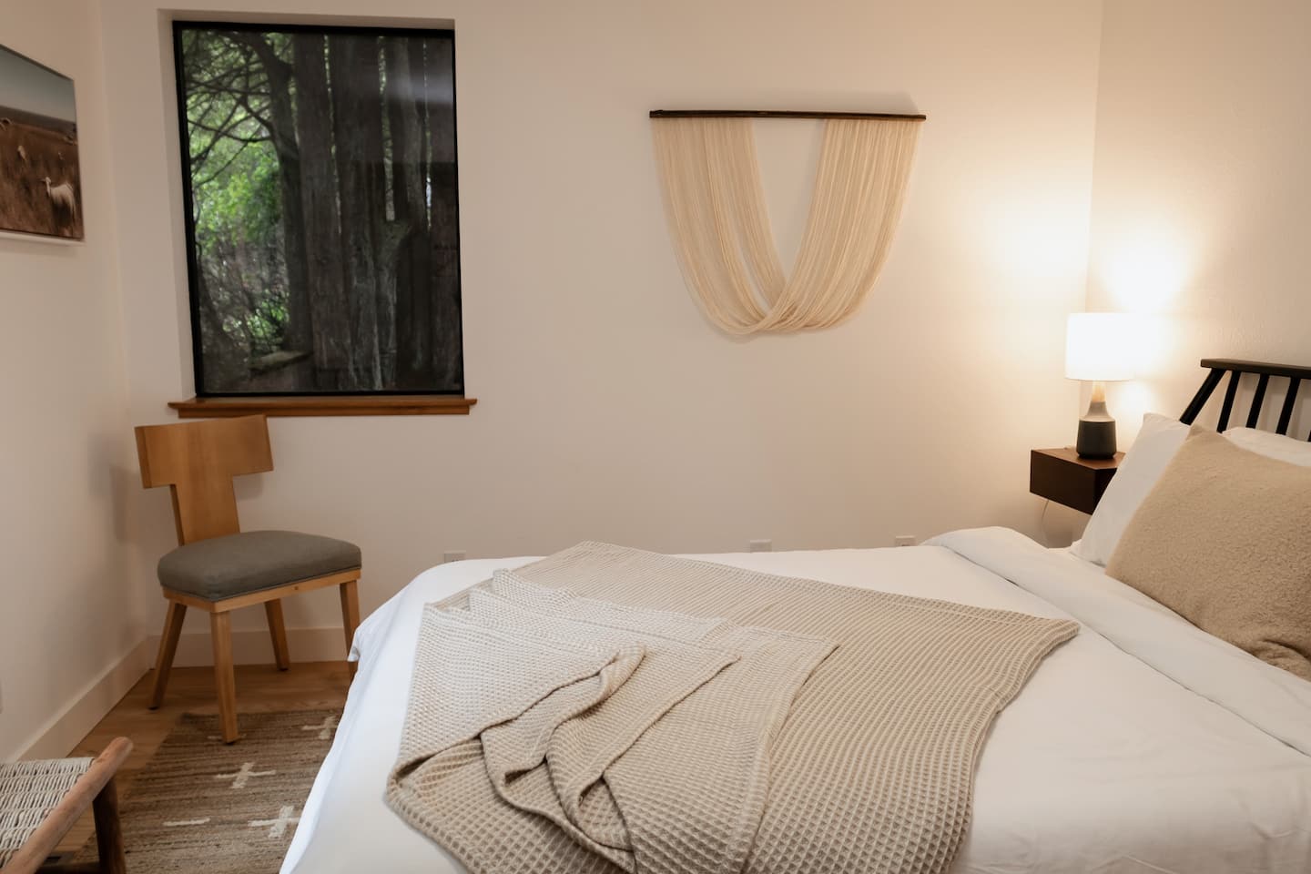 Sea Ranch bedroom with forest view window and woven wall hanging