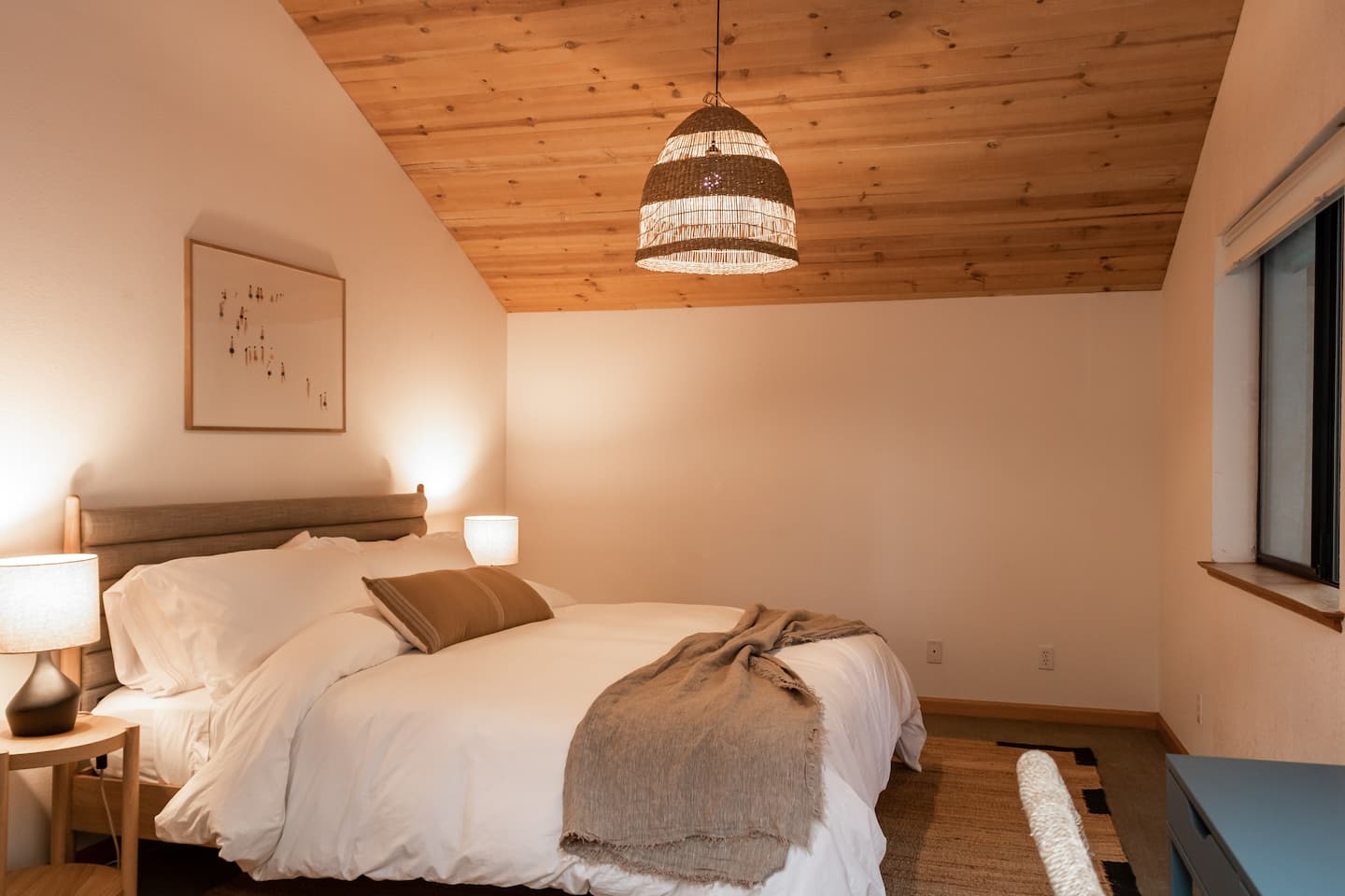 Sea Ranch bedroom with vaulted wood ceiling and woven pendant light
