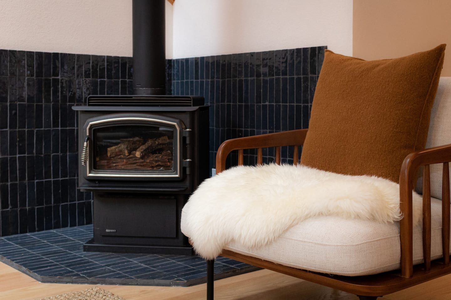 Sea Ranch wood stove fireplace beside a cozy armchair with sheepskin throw